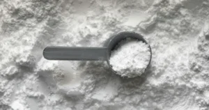 Colher-medida com colágeno em pó branco sobre uma camada de pó