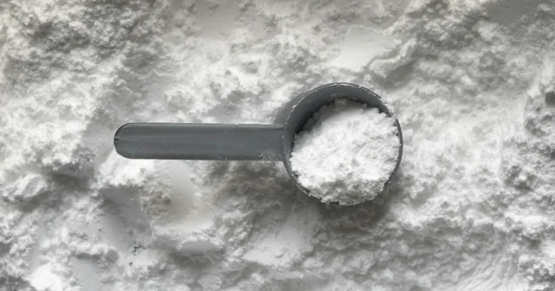 Colher-medida com colágeno em pó branco sobre uma camada de pó